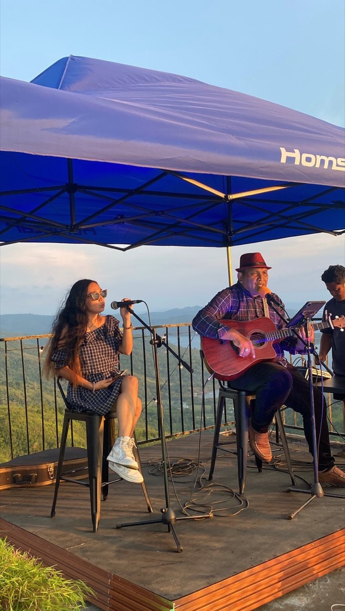 Musicians performing live on the terrace at Laaganan, the sea and islands behind them