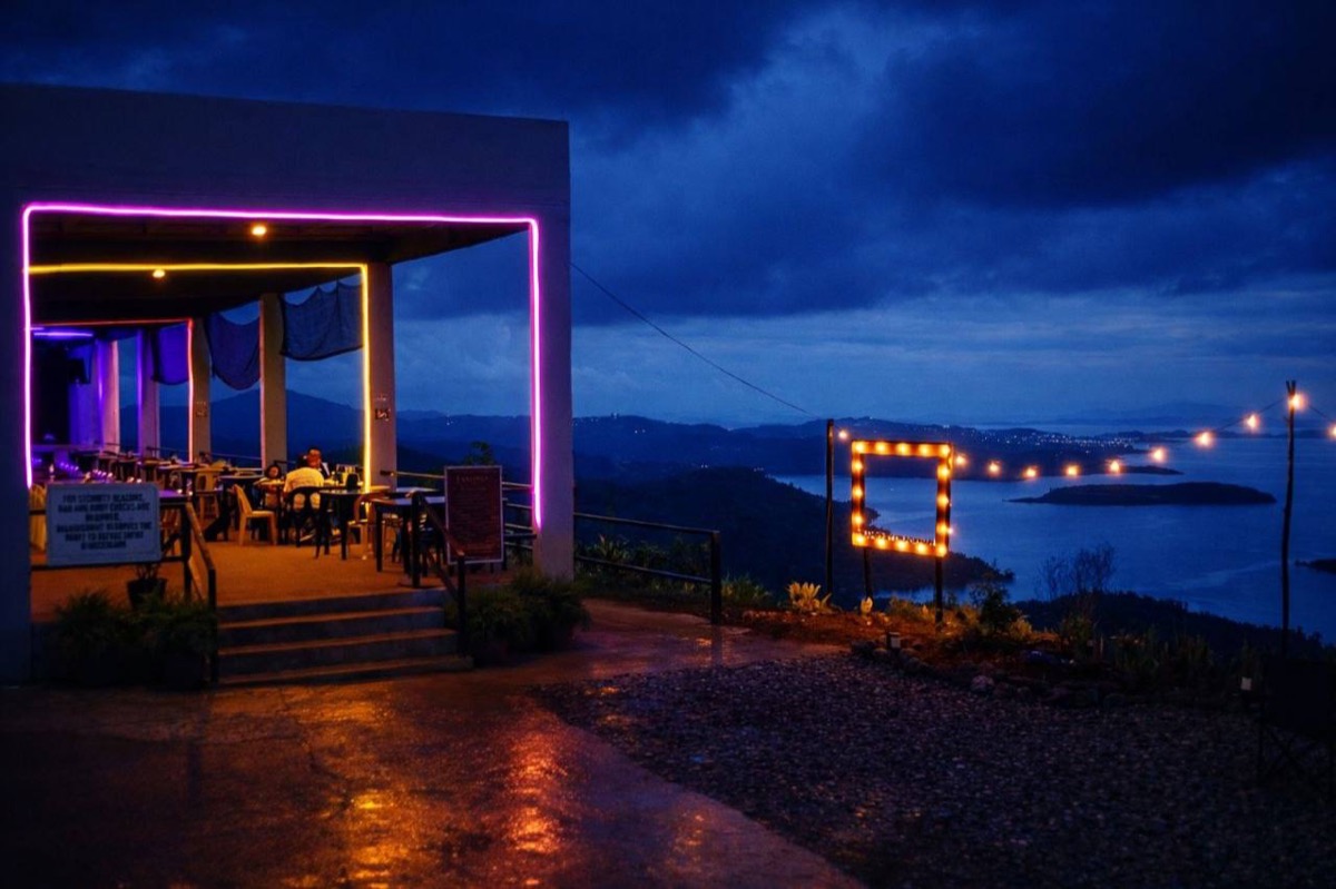 Laaganan after dark, neon and string lights along the terrace above the bay